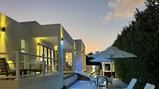 A modern outdoor patio area with a pool, lounge chairs, and a covered seating area. - The White House TCI Guest House (Providenciales)