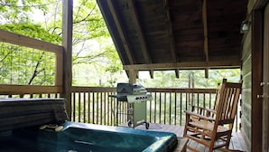 Eine Holzterrasse mit Whirlpool, Grill und Schaukelstuhl.