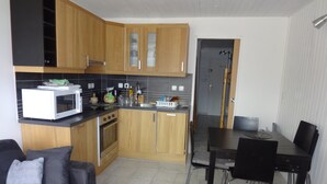 Uma cozinha compacta com armários de madeira, micro-ondas e um espaço de jantar com mesa e cadeiras.
