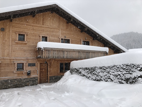 A wooden building with a snow-covered roof and a stone foundation.