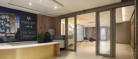 A reception area with a modern design, including a reception desk, a plant, and a view of the building's exterior.