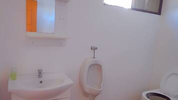 Ein Badezimmer mit Waschbecken, Urinal, Toilette und einem kleinen Fenster.