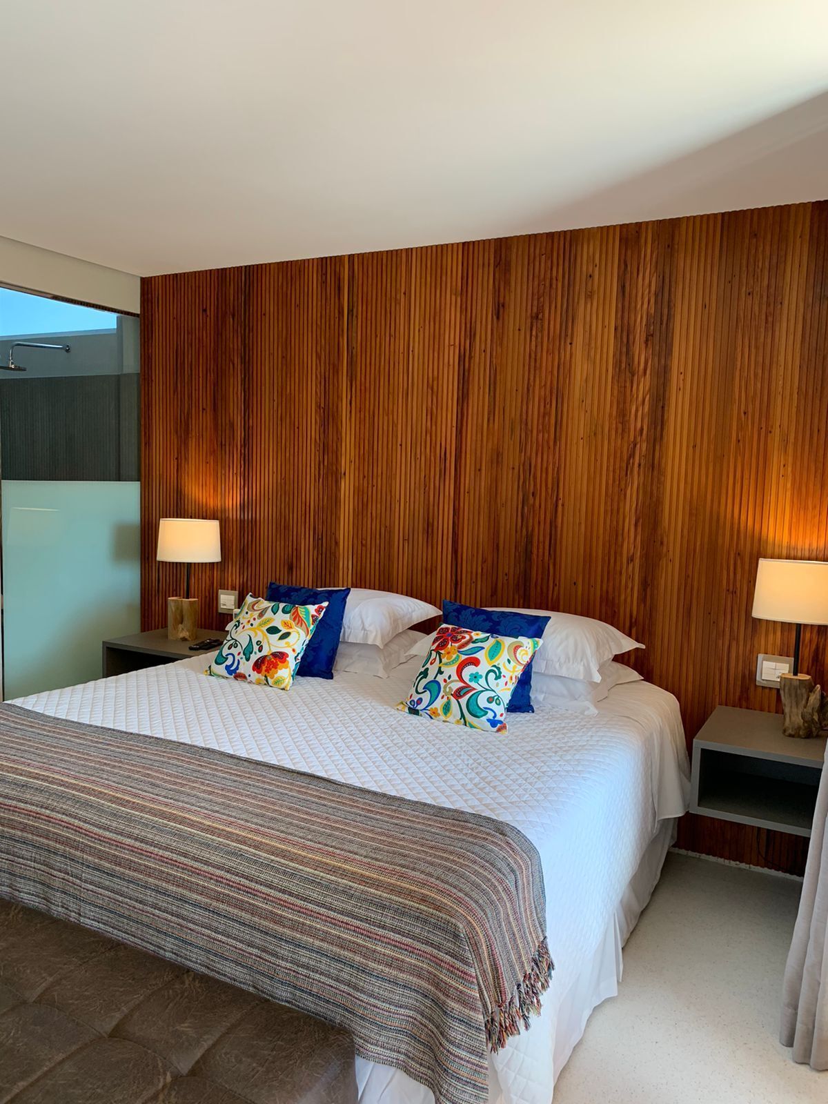 Une chambre d’hôtel moderne avec un grand lit, un mur lambrissé en bois et une vue sur le ciel.