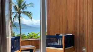 A room with a wooden partition, a bench, and a table. - Bahari Suites (Ilhabela)