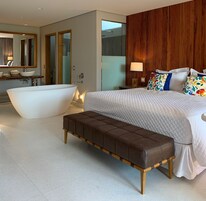 Un dormitorio moderno con una cama grande, una bañera y un banco.