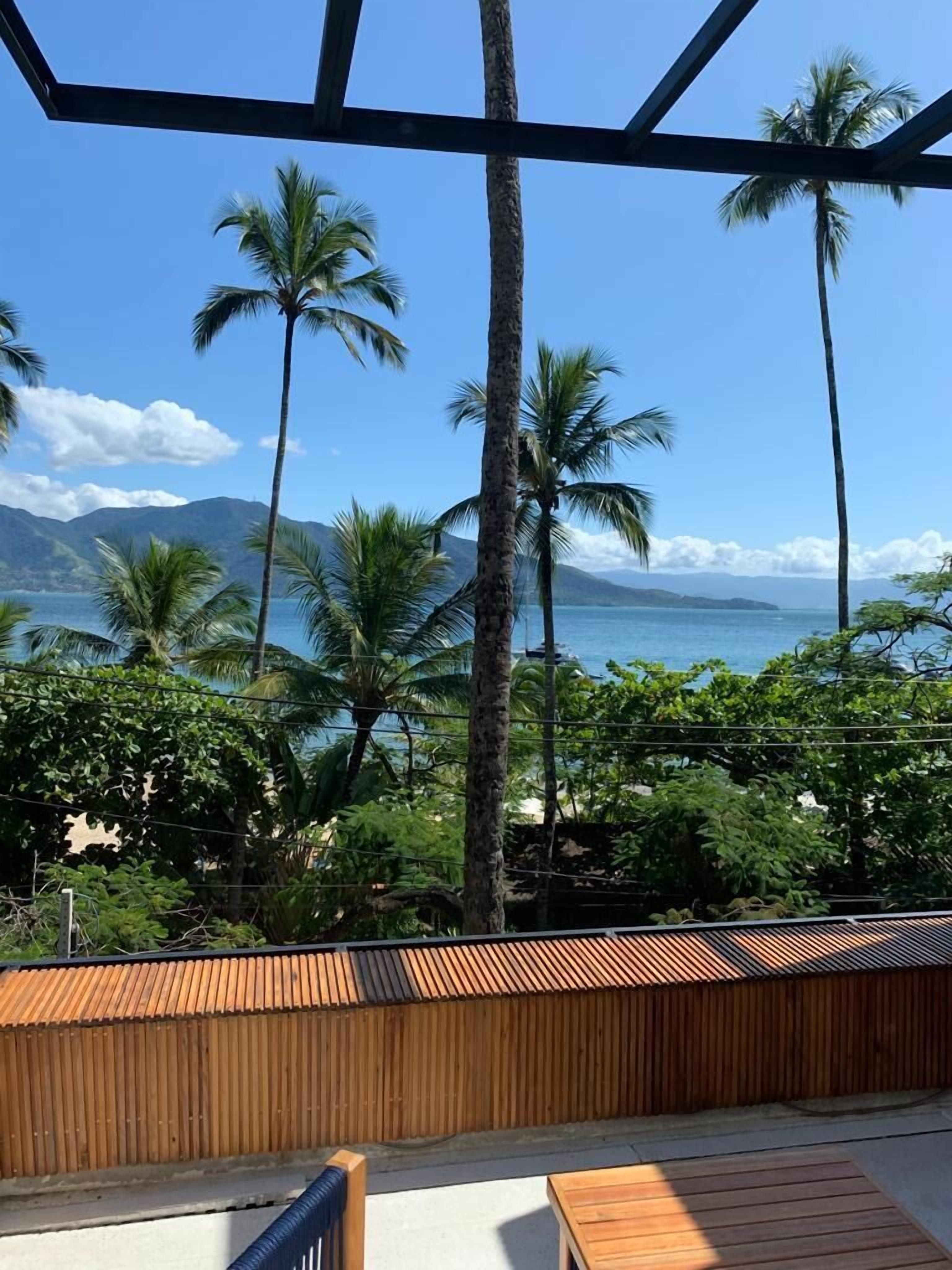 Um deck de madeira com vista para coqueiros e uma praia.