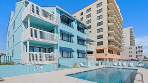 A multi-story hotel with balconies, a swimming pool, and a lifeguard sign. - Updated oceanfront condo w/pool, great location near Main St and other attractions (North Myrtle Beach)