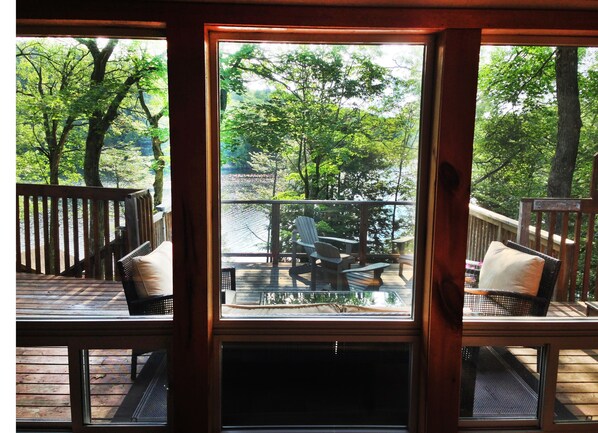 A wooden deck with outdoor seating and a view of a lake.