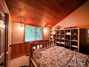 Habitació amb panells de fusta, un llit, una prestatgeria i una finestra amb persianes.