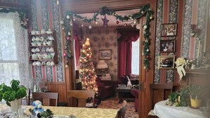 Ein gemütlicher Essbereich mit einem floralen Teppich, einem Weihnachtsbaum und einem für eine Mahlzeit gedeckten Tisch.