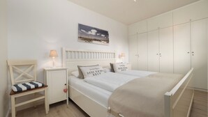 A bedroom with a bed, nightstands, a chair, a wardrobe, and a ceiling light fixture.
