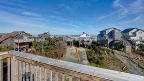 A coastal residential area with multiple houses, some elevated on stilts, and a clear view of the ocean. - Semi-Oceanfront home with direct access to the beach! (Avon)