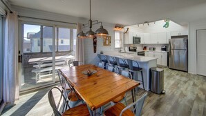 A modern kitchen with white cabinets, stainless steel appliances, and a wooden dining table with chairs. - Semi-Oceanfront home with direct access to the beach! (Avon)