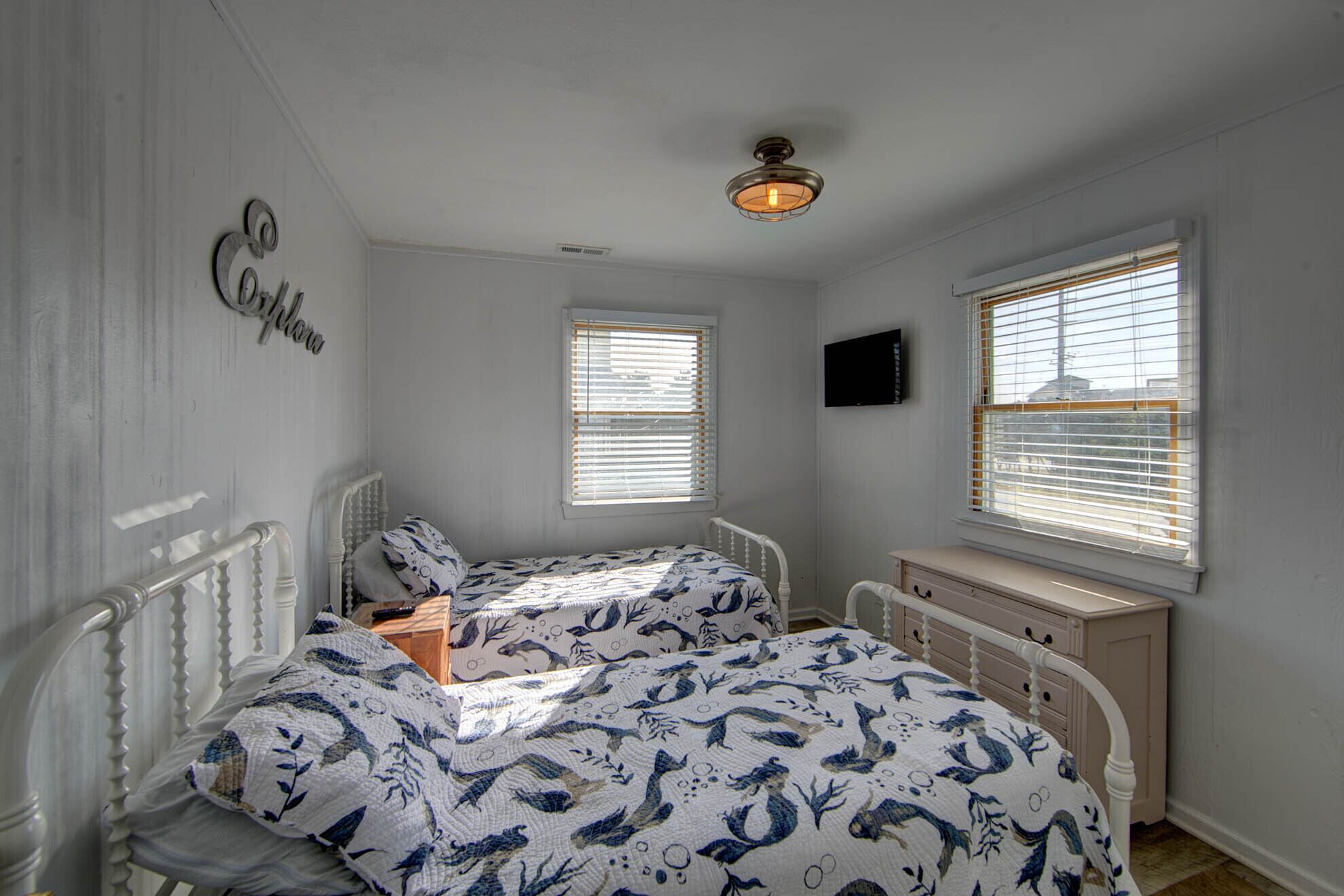 Une chambre avec deux lits, une commode et un ventilateur de plafond.