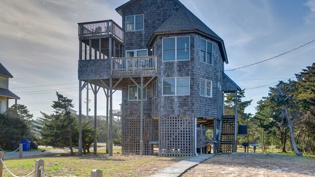 A multi-level wooden structure with balconies and a covered outdoor area. - Semi-Oceanfront home with direct access to the beach! (Avon)