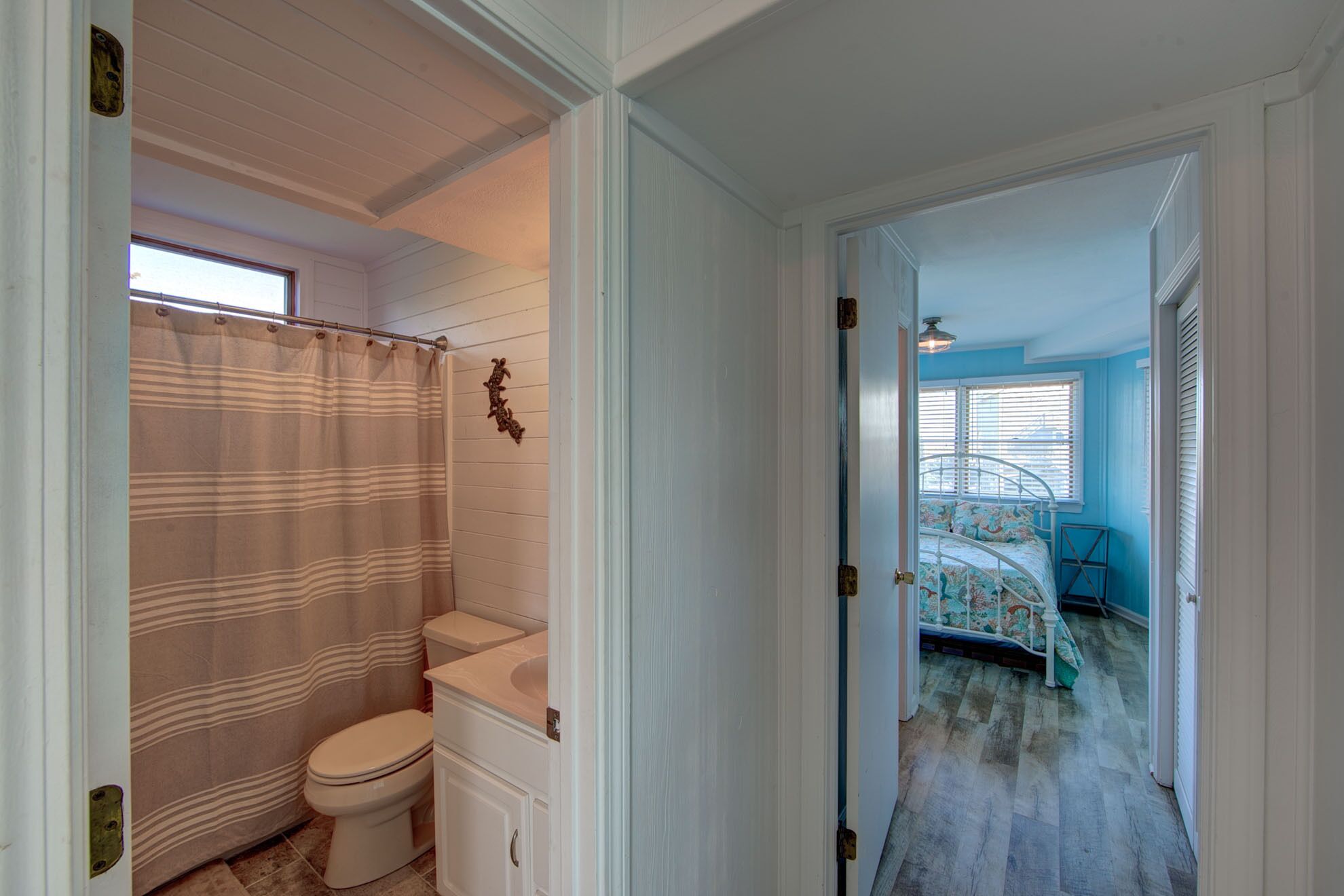 A bathroom with a striped shower curtain, a toilet, and a sink.