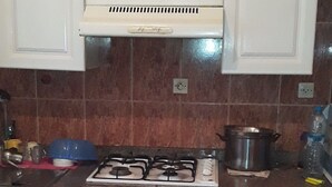 Eine Küche mit weißen Schränken, einem Gasherd, einem Backofen und einer Mikrowelle.