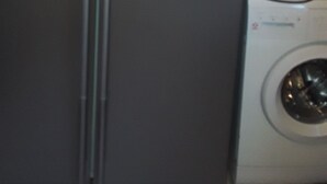 Eine kompakte Küche mit Edelstahl-Kühlschrank, Waschmaschine und Wasserspender.