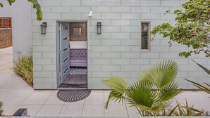 Un edificio moderno con fachada gris, una pequeña entrada con puerta y un área de estar en el interior.