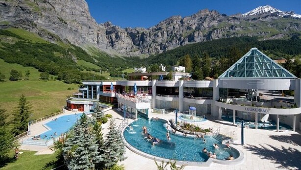 Ein Hotel mit mehreren Schwimmbecken, einem Bergpanorama und modernem architektonischem Design.