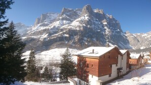 Eine Berglodge mit Holzfassade, schneebedeckten Dächern und Blick auf zerklüftete Berge.