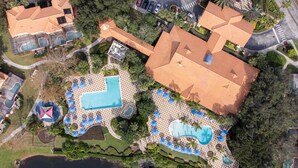 Vue aérienne d’un complexe hôtelier doté de nombreuses piscines, d’une grande piscine centrale et d’un lac.