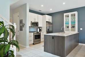 A modern kitchen with white cabinets, stainless steel appliances, and a grey island. - Disney Dream Villa w/Pool 5 Miles to the Parks! (Kissimmee)