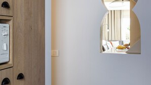 Ein Flur mit einer Holzwand links und einem Wandspiegel, der einen Essbereich reflektiert.