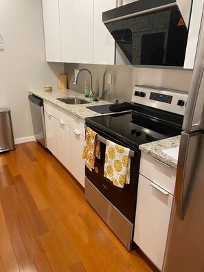 Una cocina moderna con armarios blancos, lavavajillas de acero inoxidable, horno doble y refrigerador.