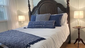 Una camera da letto con un letto grande, una testiera in legno, un comodino con una lampada e un condizionatore d'aria a parete.