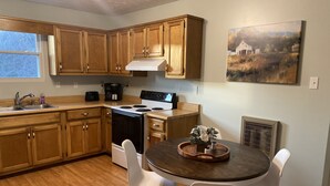 Una cucina con mobili in legno, un piano cottura, un lavello e un tavolo da pranzo con sedie.