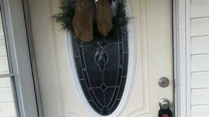 Una porta d'ingresso con tappetino di benvenuto, serratura a chiave e ghirlanda decorativa.