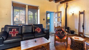 A cozy living room with a black leather sofa, wooden coffee table, and a rustic chair.