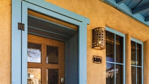 A building with a blue-framed door, a wooden bench, and a wall-mounted light fixture.