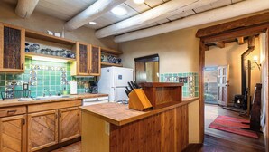 A rustic kitchen with wooden cabinets, a central island, and a tiled backsplash.