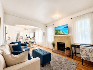 Een woonkamer met een open haard, een televisie en een eethoek.