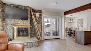 A living room with a stone fireplace, a leather sofa, and a dining area with a wooden table and chairs.