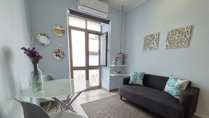 Una sala de estar moderna con una mesa de vidrio, un sofá gris y elementos decorativos en la pared.