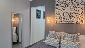 Una habitación con un espejo, un adorno en la pared, un sofá con cojines estampados y una señal enmarcada en la pared.