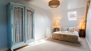 Een slaapkamer met een bed, twee bedlampen, een kledingkast en een raam.