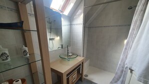 Een badkamer met een douchecabine van glas, een glazen wastafel en een houten wastafelmeubel.