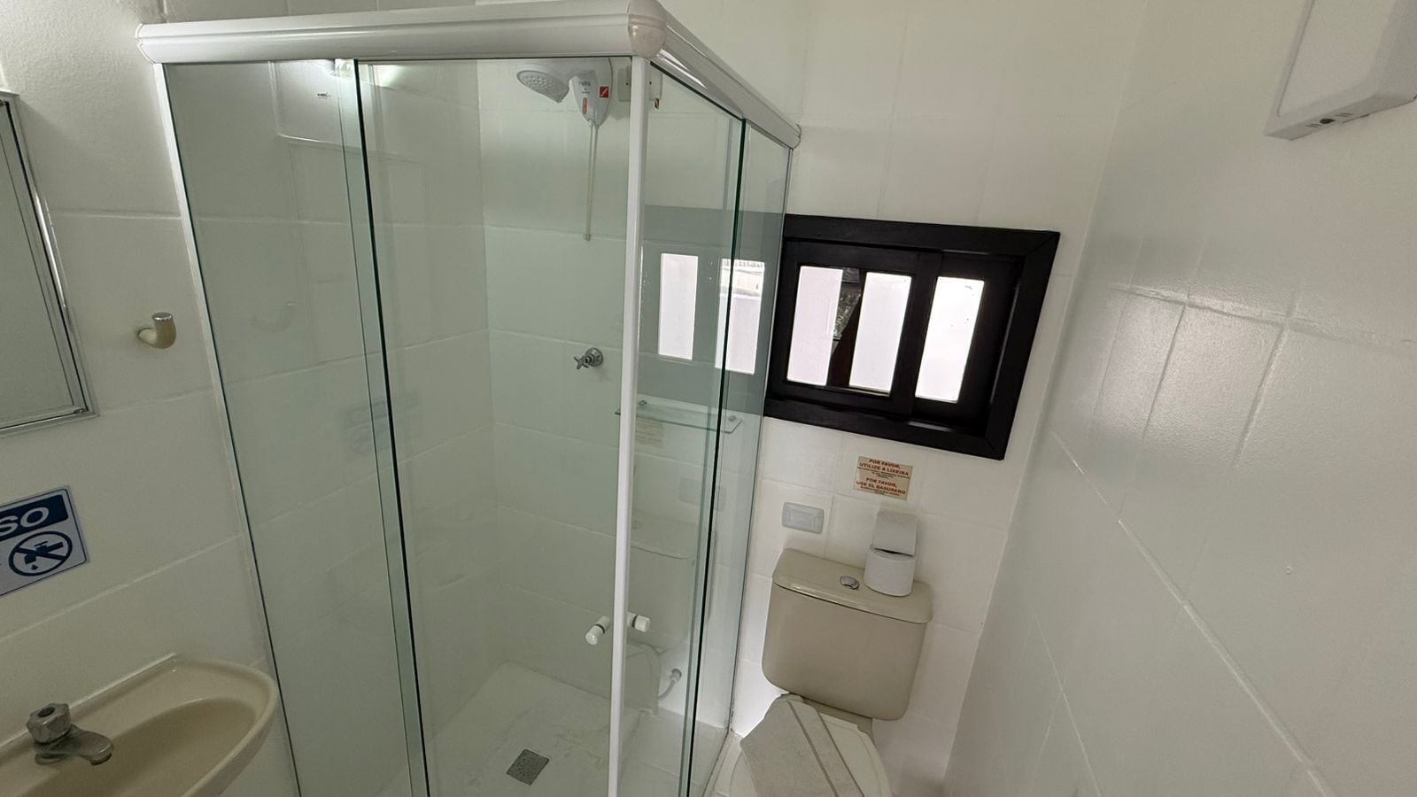 Un baño con ducha de vidrio, inodoro y lavamanos.