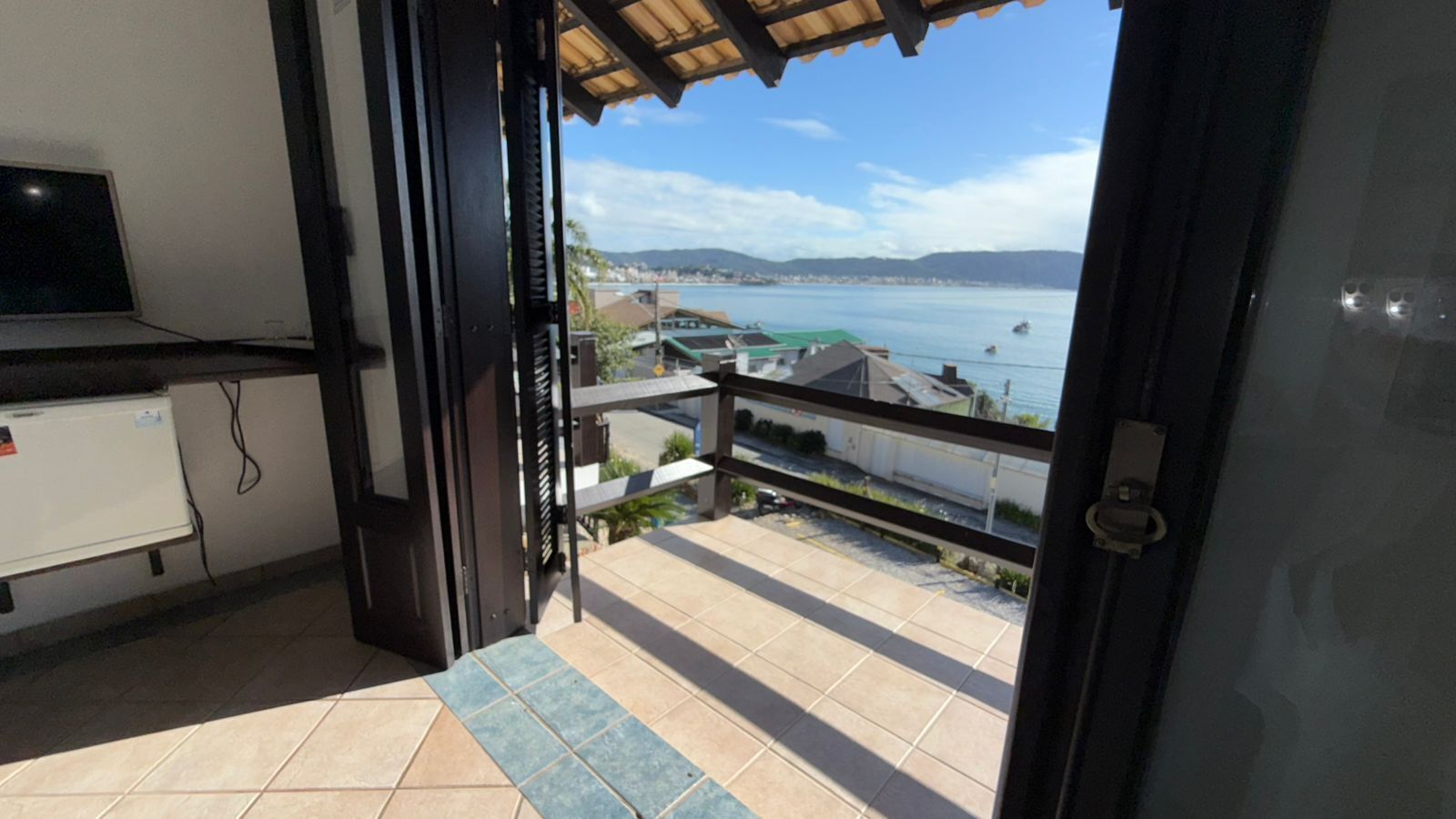 A balcony with a view of the sea and a distant cityscape.