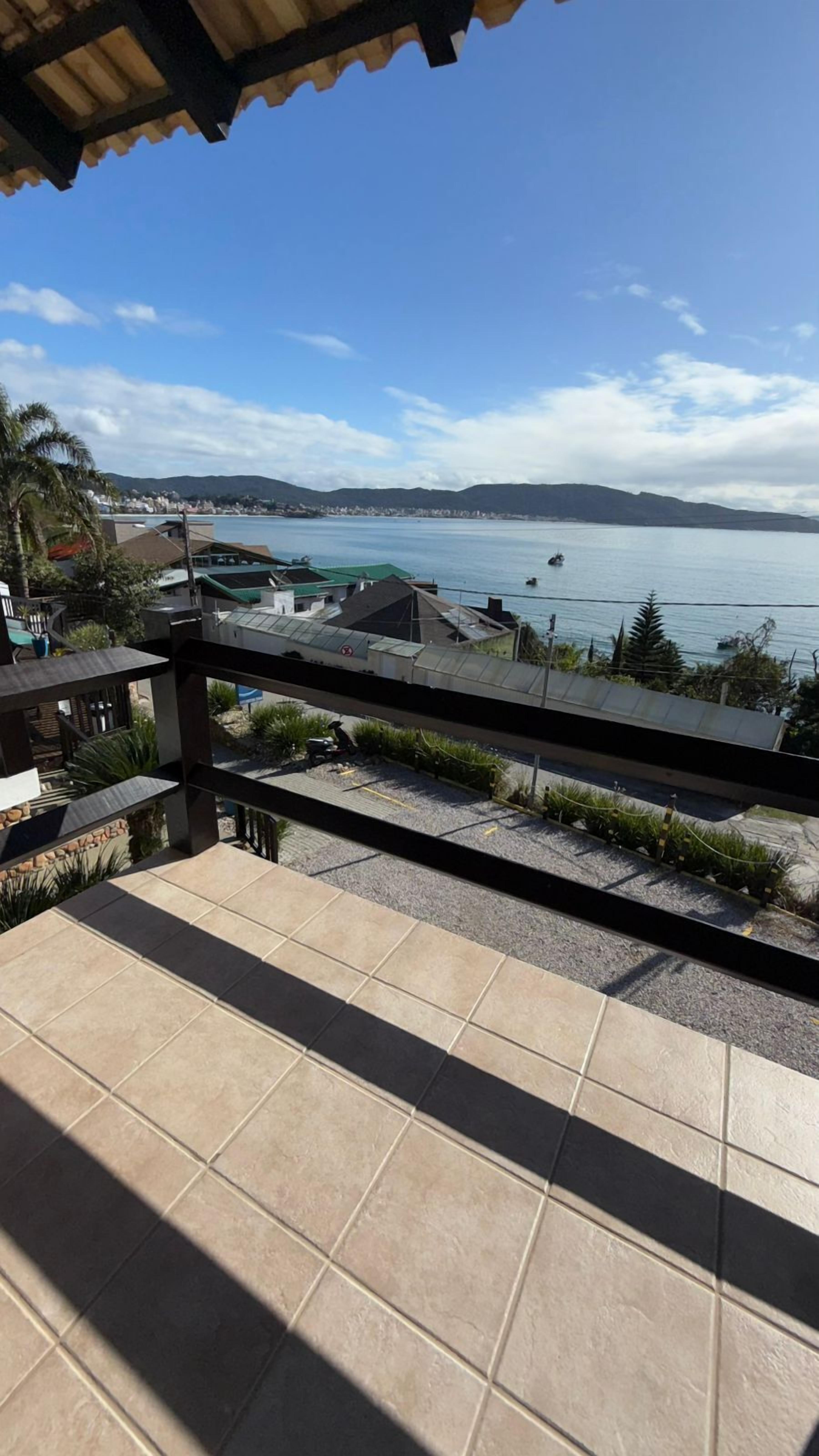 A balcony with a view of a calm sea and distant mountains.