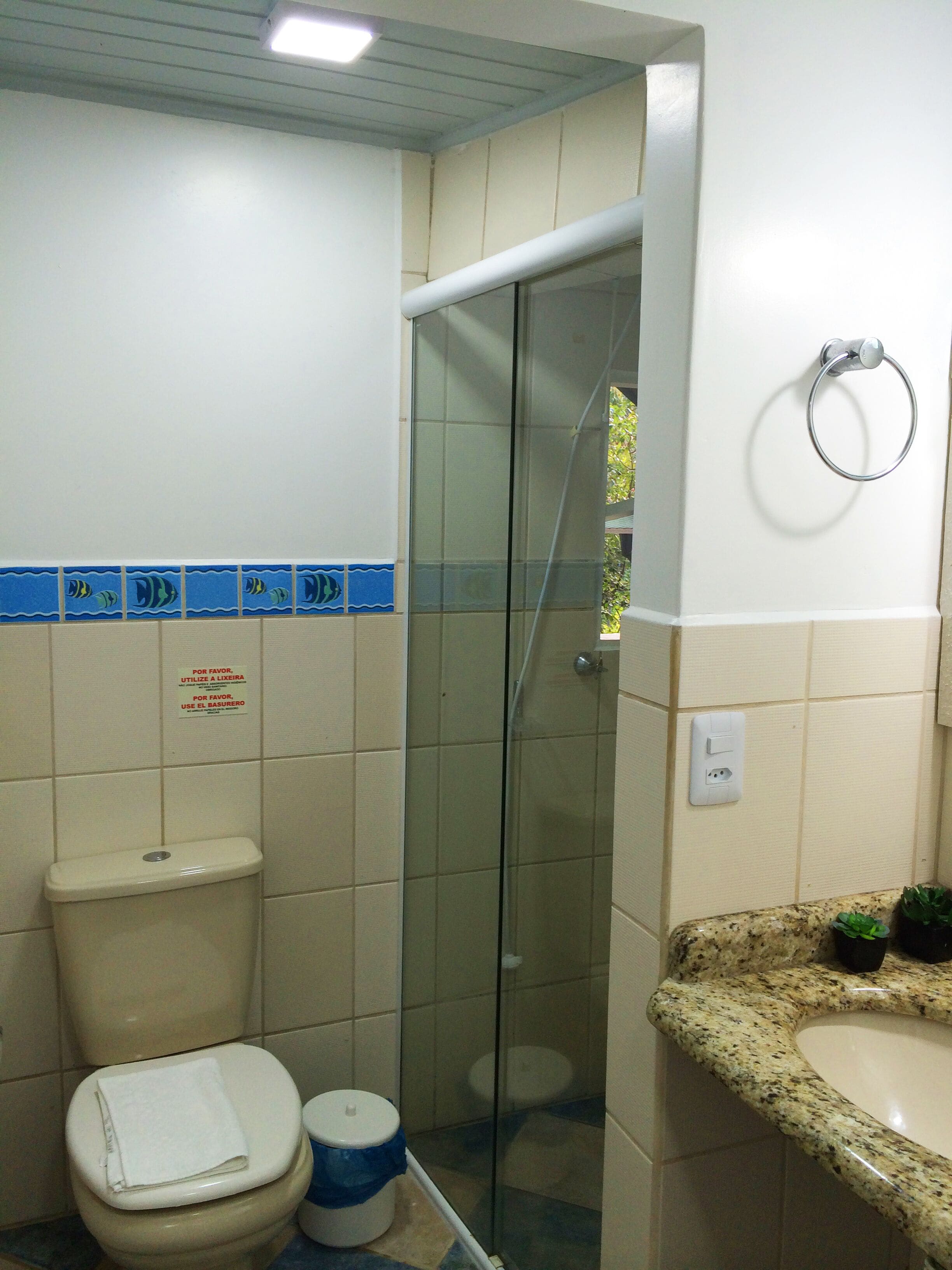 Ein Badezimmer mit Toilette, einer Duschkabine aus Glas und einem Waschbecken mit Granitplatte.