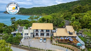 Un hotel junto a la costa con techo de tejas, piscina y vista al mar.