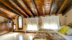 Un dormitorio con techo de madera, cama con manta de piel y ventana con cortinas.
