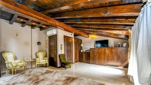 Una habitación amplia con un gran felpudo de piel, vigas de madera en el techo, un televisor y una zona de cocina con armarios de madera.