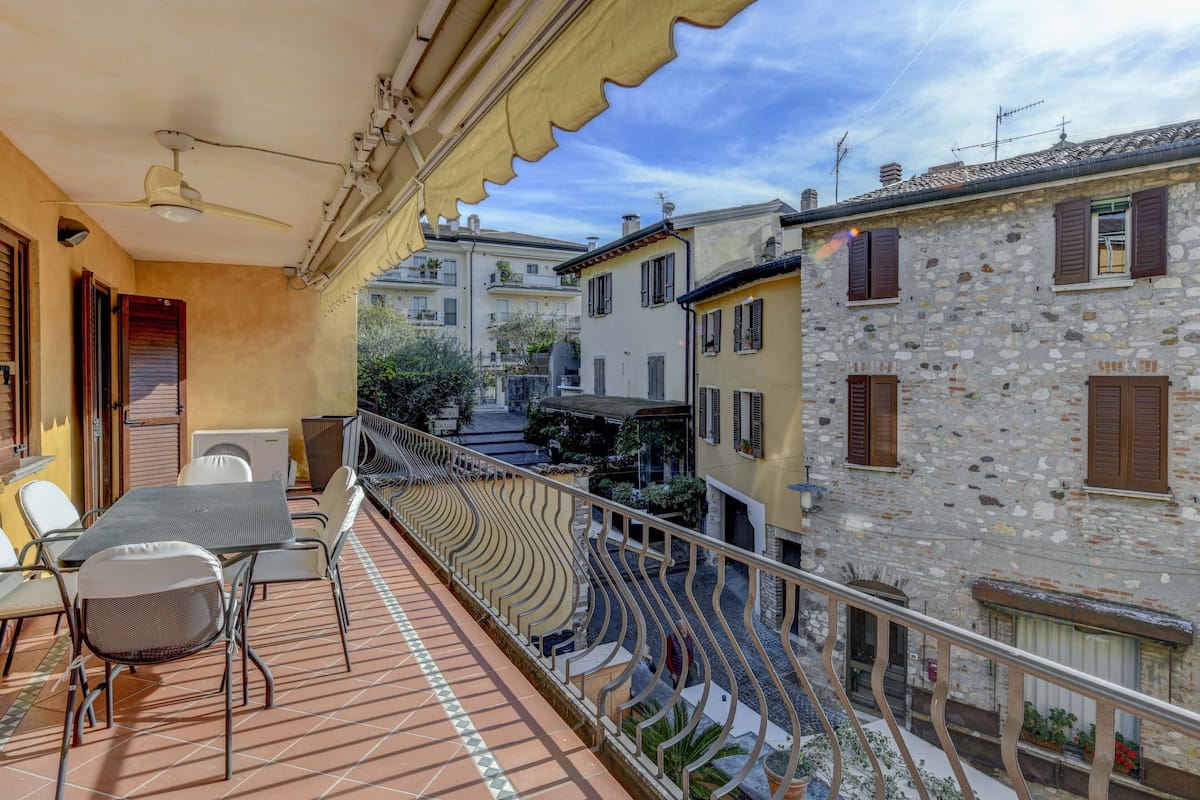 Ein Balkon mit Tisch und Stühlen, mit Blick auf eine Straße mit Gebäuden.