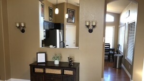 A hallway with a dark wooden console table, wall-mounted sconces, and framed artwork. - Lavender Lane (Phoenix)